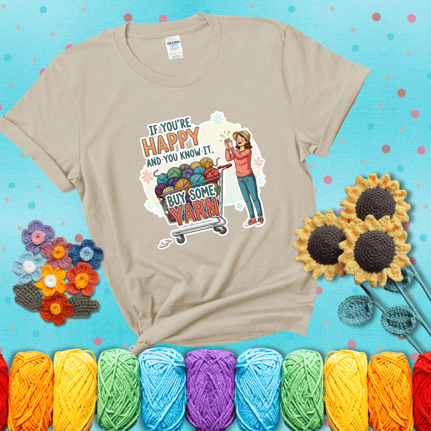 Woman clapping beside a shopping cart overflowing with colorful yarn balls, styled with cheerful pastel accents and bold playful lettering showing a beige tee with a teal sunflower background