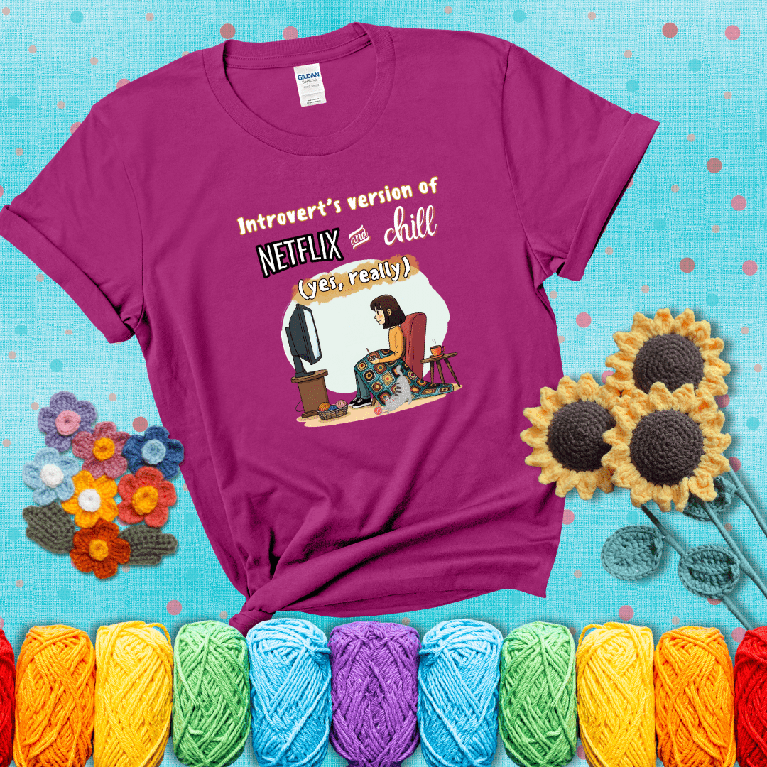 A girl with a crochet hook sits under a granny square blanket watching TV, with yarn, a coffee mug, and a cat at her feet. Text says “Introvert’s version of Netflix and chill (yes, really)," showing a magenta tee with a teal sunflower background