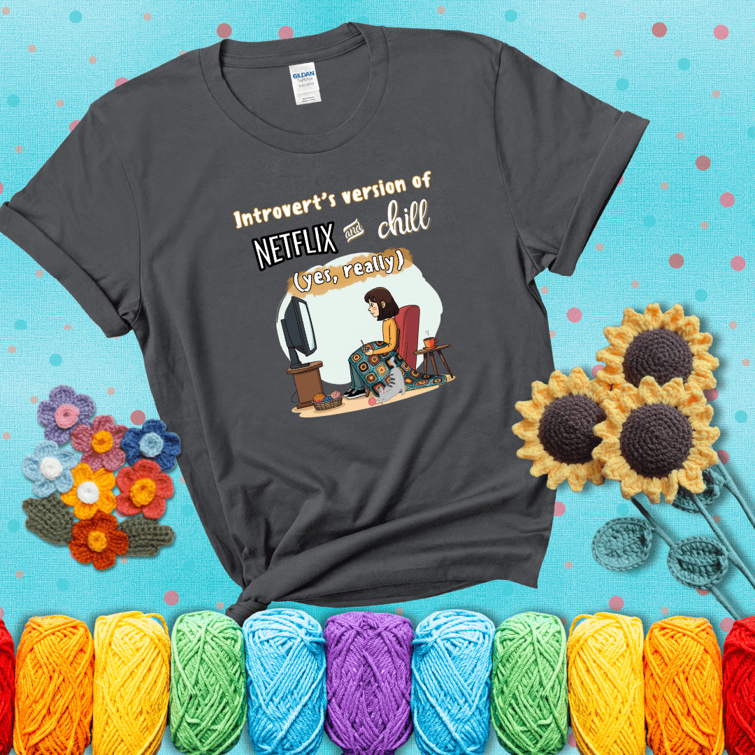 A girl with a crochet hook sits under a granny square blanket watching TV, with yarn, a coffee mug, and a cat at her feet. Text says “Introvert’s version of Netflix and chill (yes, really)," showing a dark grey tee with a teal sunflower background