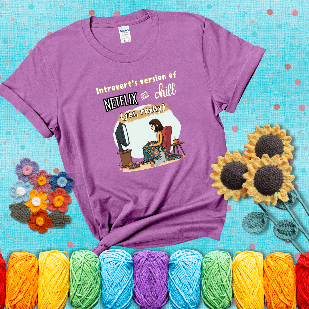 A girl with a crochet hook sits under a granny square blanket watching TV, with yarn, a coffee mug, and a cat at her feet. Text says “Introvert’s version of Netflix and chill (yes, really)," showing a light purple tee with a teal sunflower background