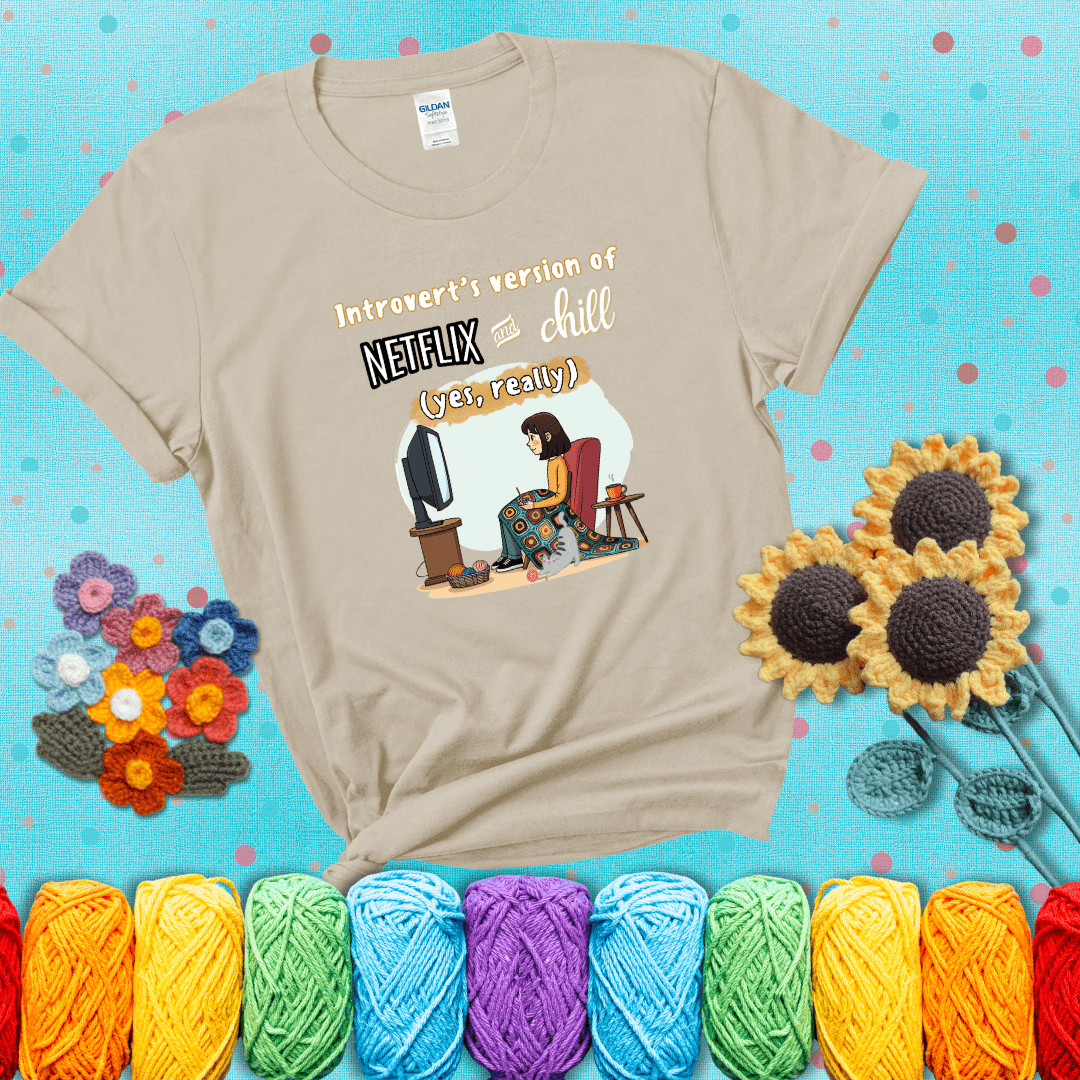 A girl with a crochet hook sits under a granny square blanket watching TV, with yarn, a coffee mug, and a cat at her feet. Text says “Introvert’s version of Netflix and chill (yes, really)," showing a beige tee with a teal sunflower background