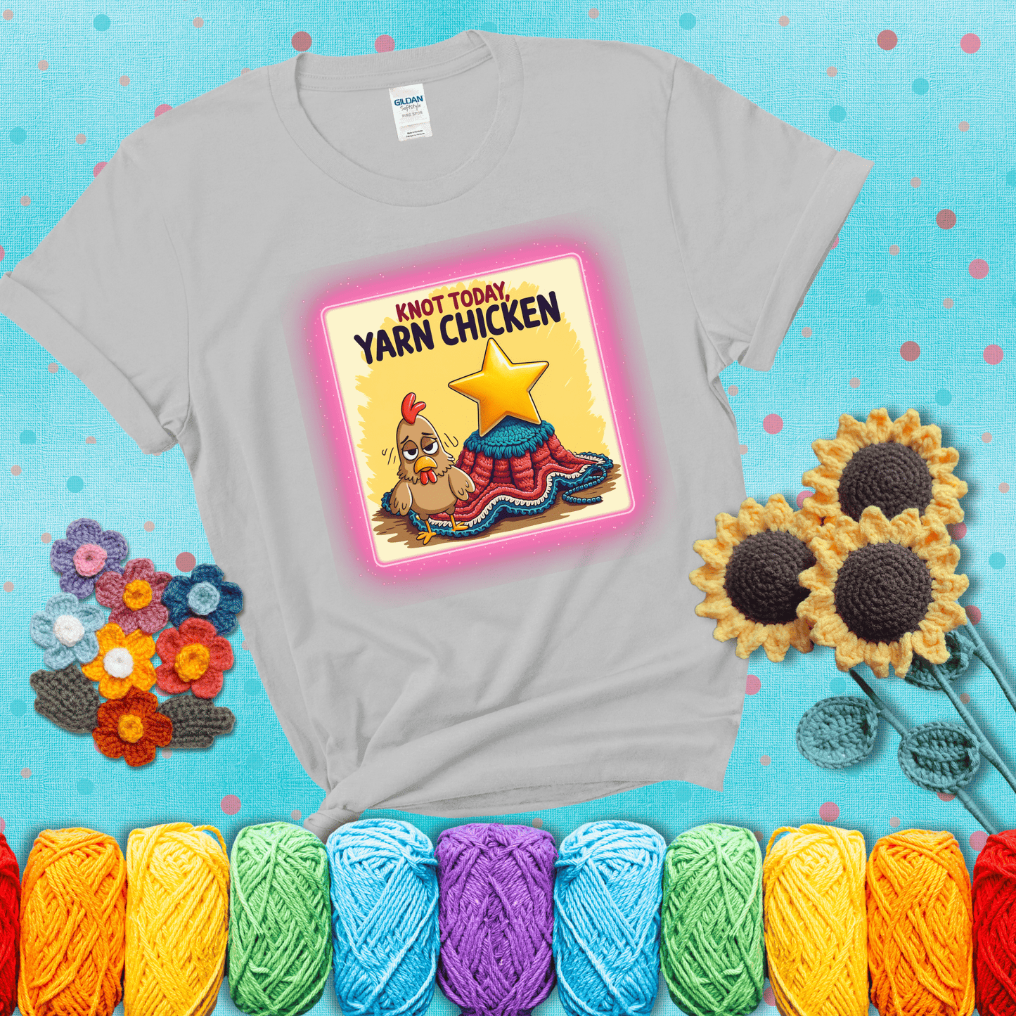 A frazzled cartoon chicken stands next to a nearly-finished project with minimal yarn left, with the phrase “Knot Today, Yarn Chicken” above, showing a light grey tee with a teal sunflower background