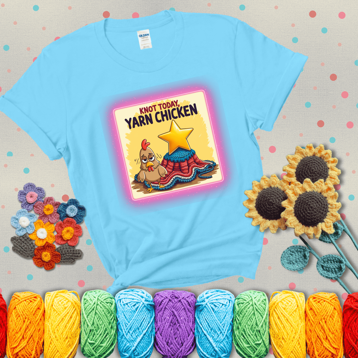 A frazzled cartoon chicken stands next to a nearly-finished project with minimal yarn left, with the phrase “Knot Today, Yarn Chicken” above, showing a light blue tee with grey sunflower background