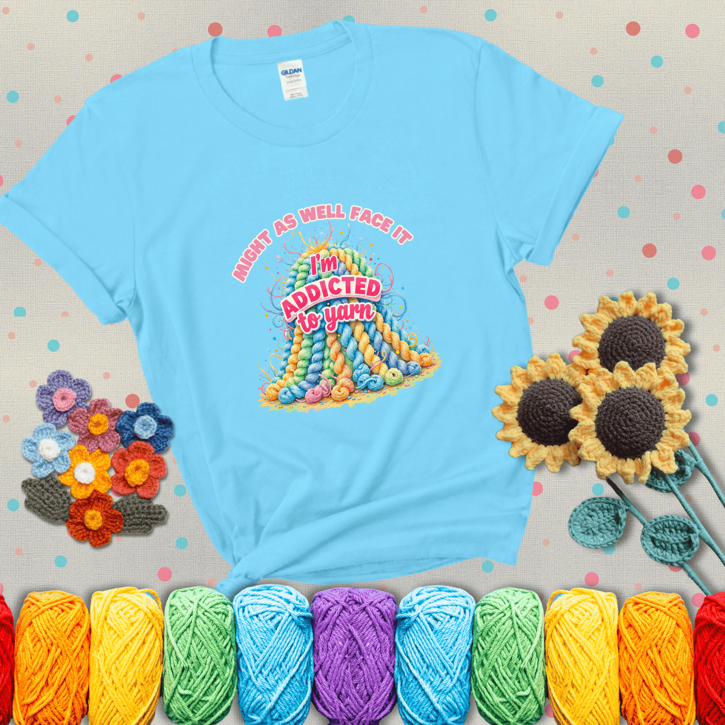 Colorful mountain of pastel yarn hanks with the phrase “Might as well face it, I’m addicted to yarn” in playful pink and red lettering showing a light blue tee with grey sunflower background
