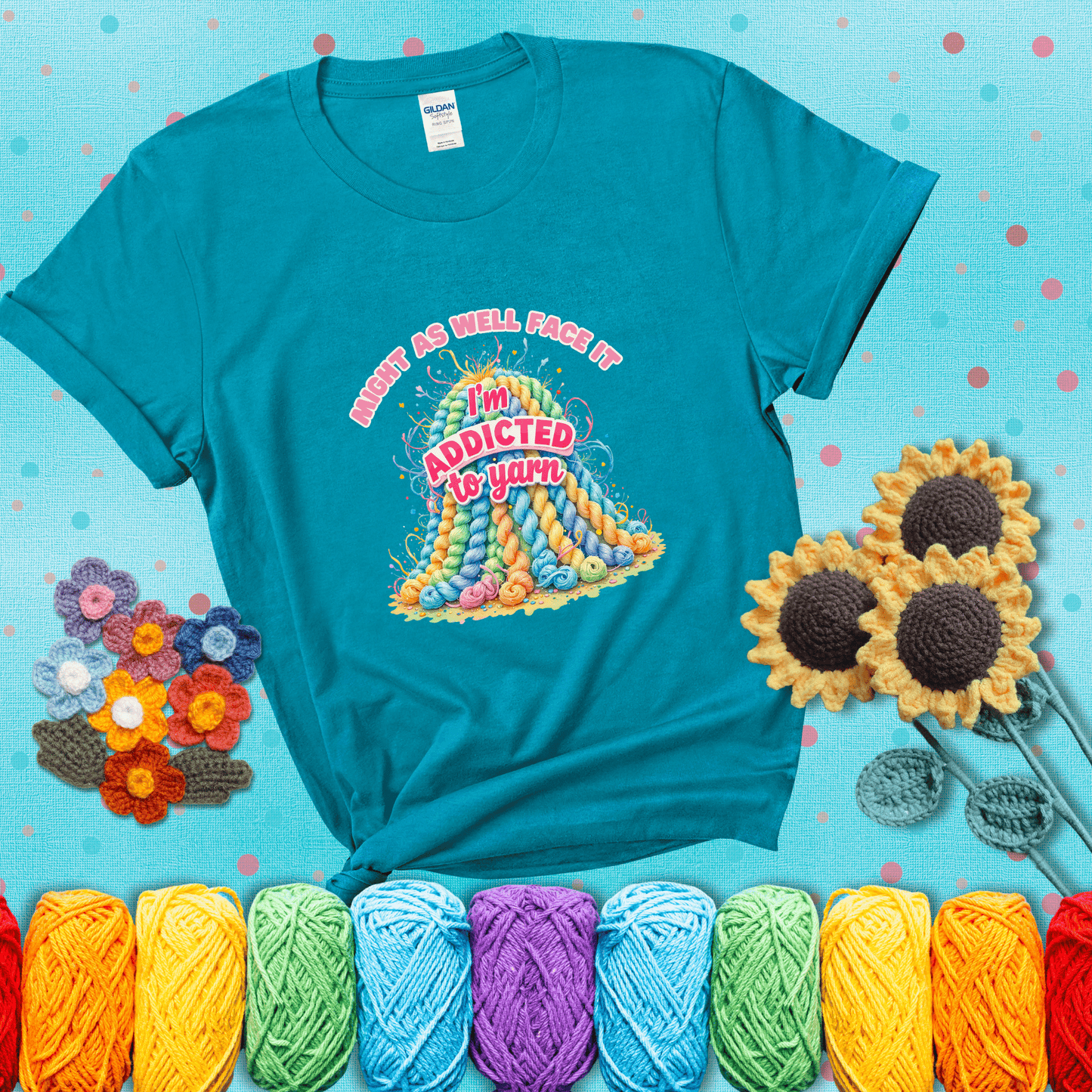 Colorful mountain of pastel yarn hanks with the phrase “Might as well face it, I’m addicted to yarn” in playful pink and red lettering showing a blue-green tee with a teal sunflower background