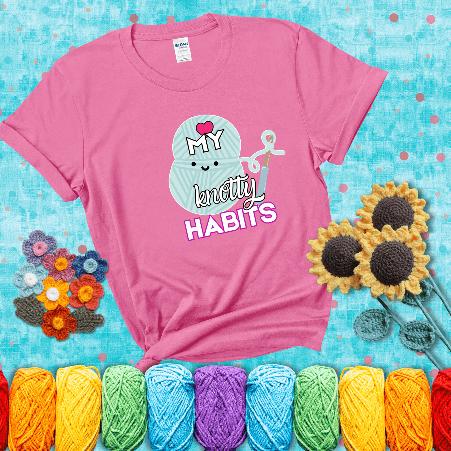 Smiling yarn ball and hook with text “Love My Knotty Habits” - cute crochet shirt with playful design for makers, showing a pink tee with a teal sunflower background