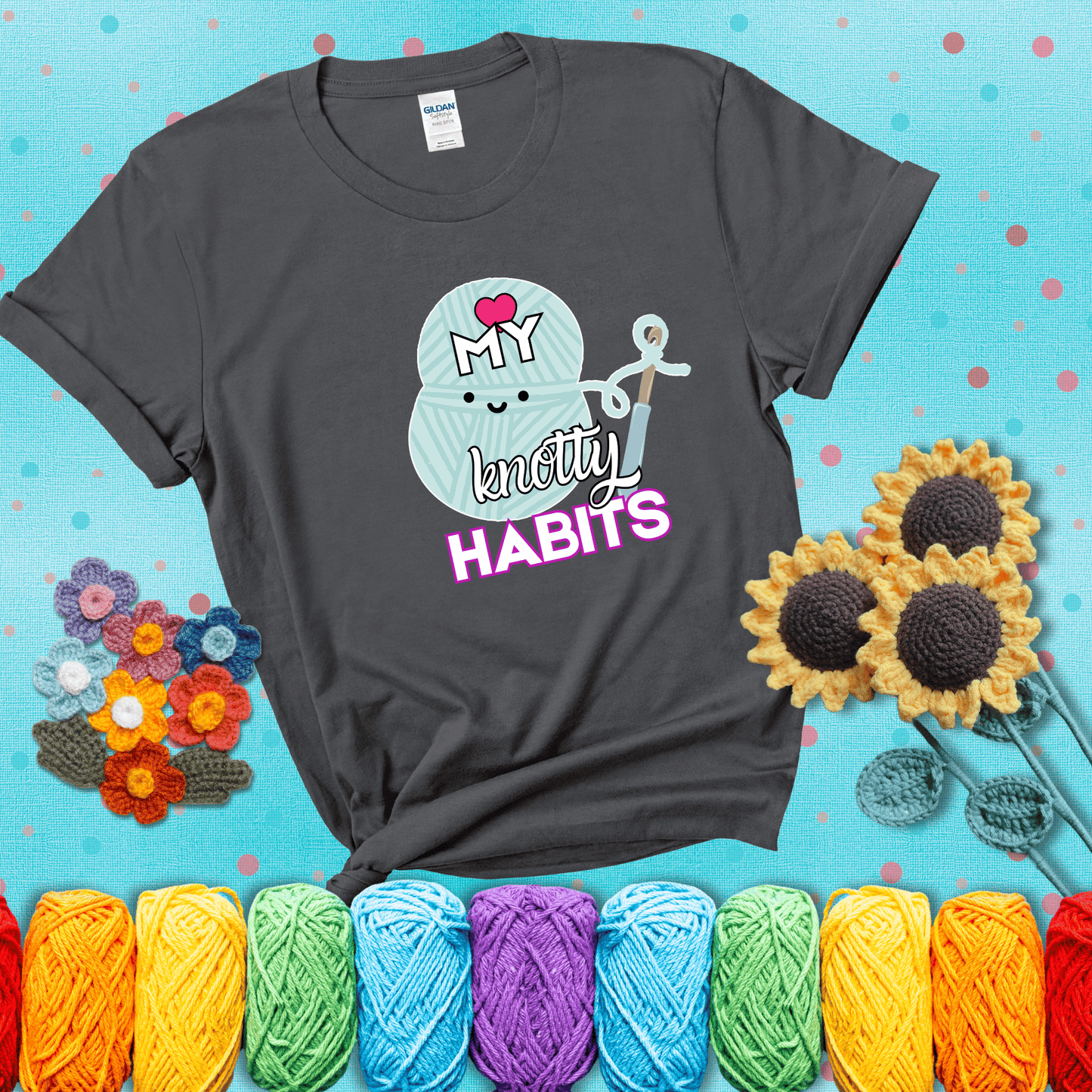 Smiling yarn ball and hook with text “Love My Knotty Habits” - cute crochet shirt with playful design for makers, showing a dark grey tee with a teal sunflower background