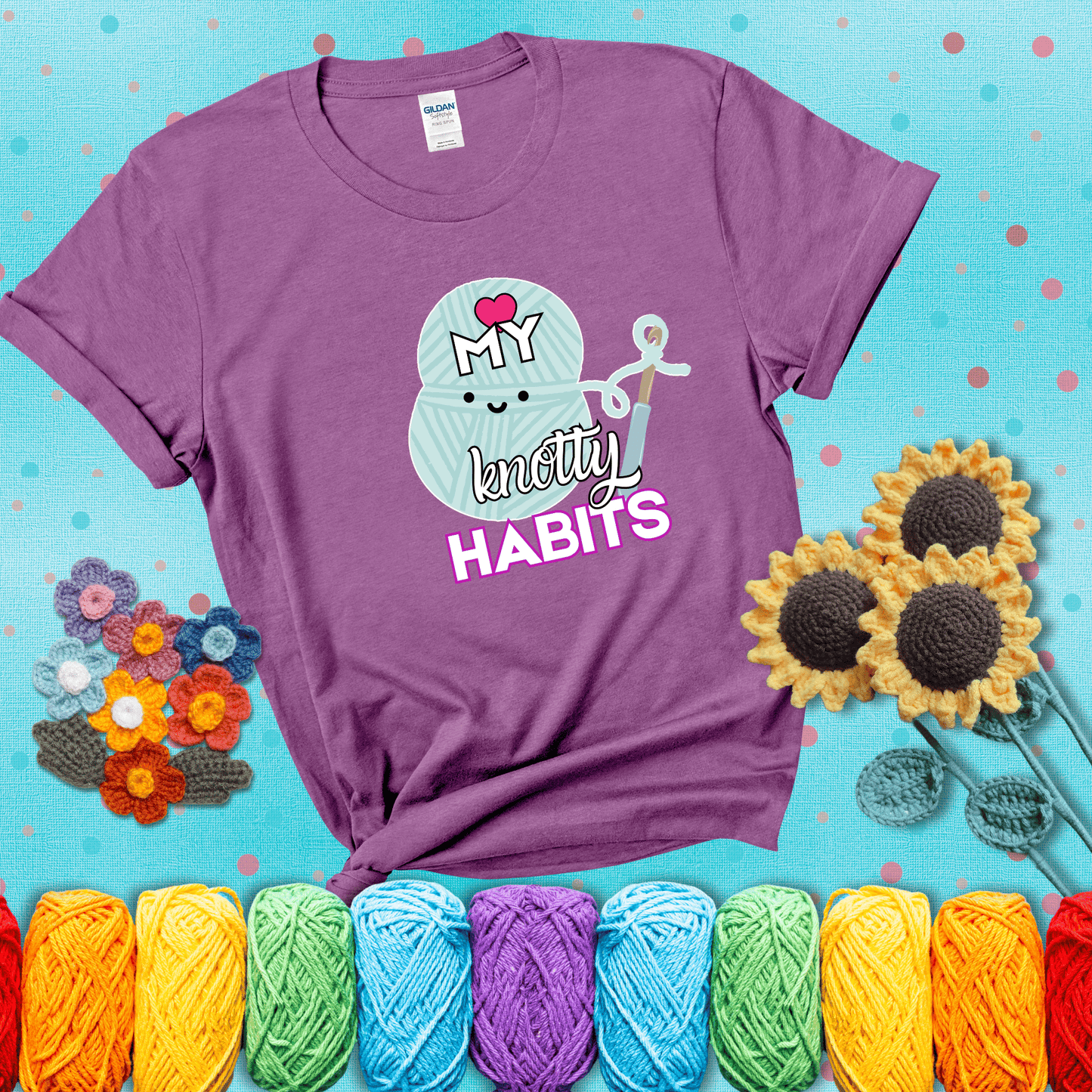 Smiling yarn ball and hook with text “Love My Knotty Habits” - cute crochet shirt with playful design for makers, showing a light purple tee with a teal sunflower background