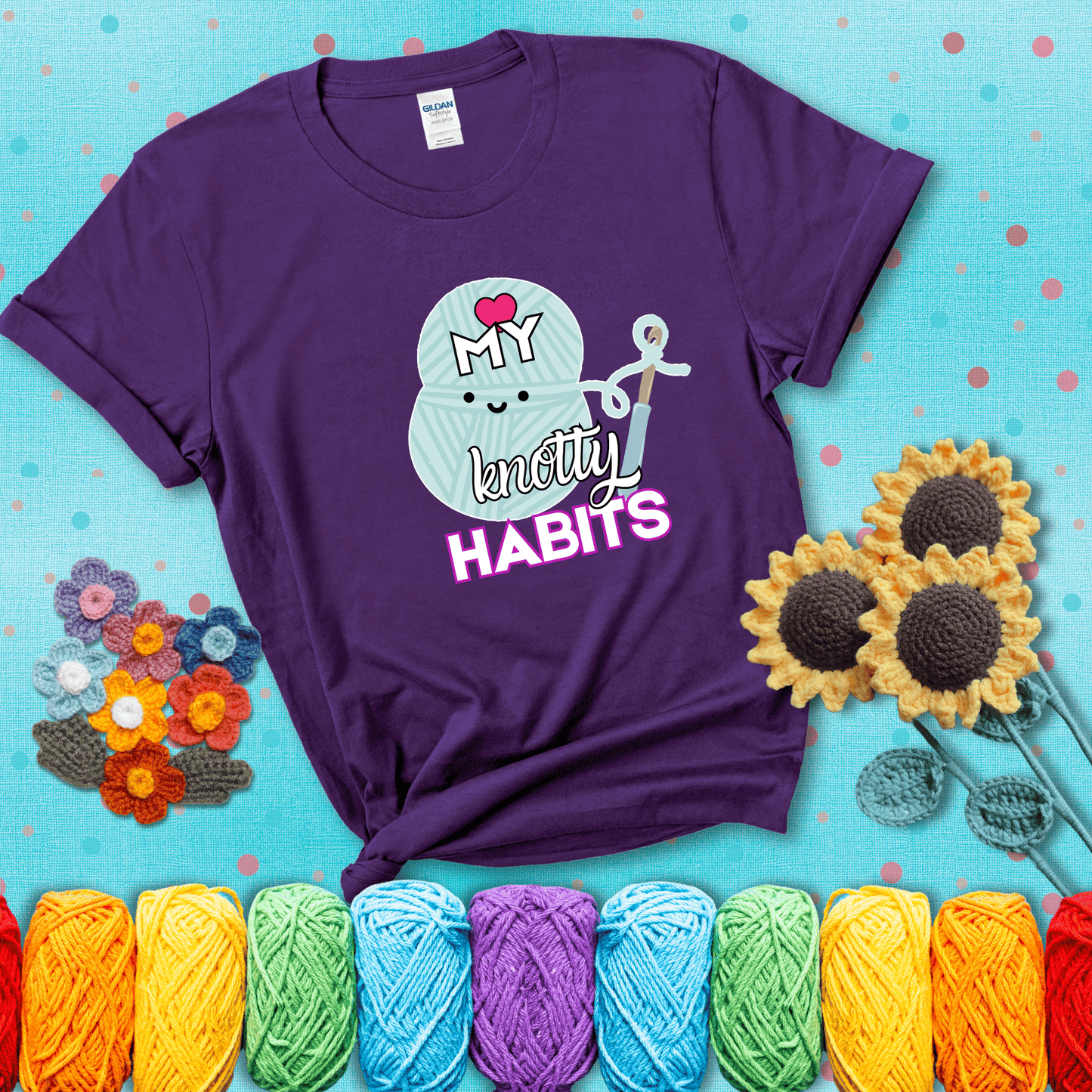 Smiling yarn ball and hook with text “Love My Knotty Habits” - cute crochet shirt with playful design for makers, showing a purple tee with a teal sunflower background