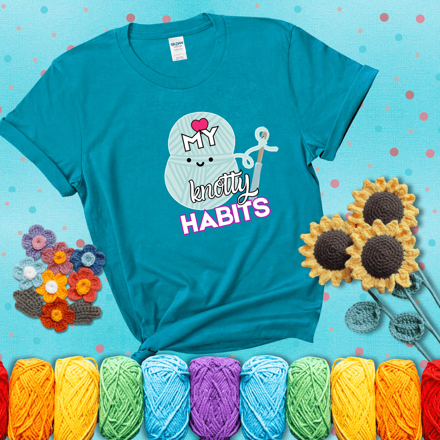 Smiling yarn ball and hook with text “Love My Knotty Habits” - cute crochet shirt with playful design for makers, showing a blue-green tee with a teal sunflower background