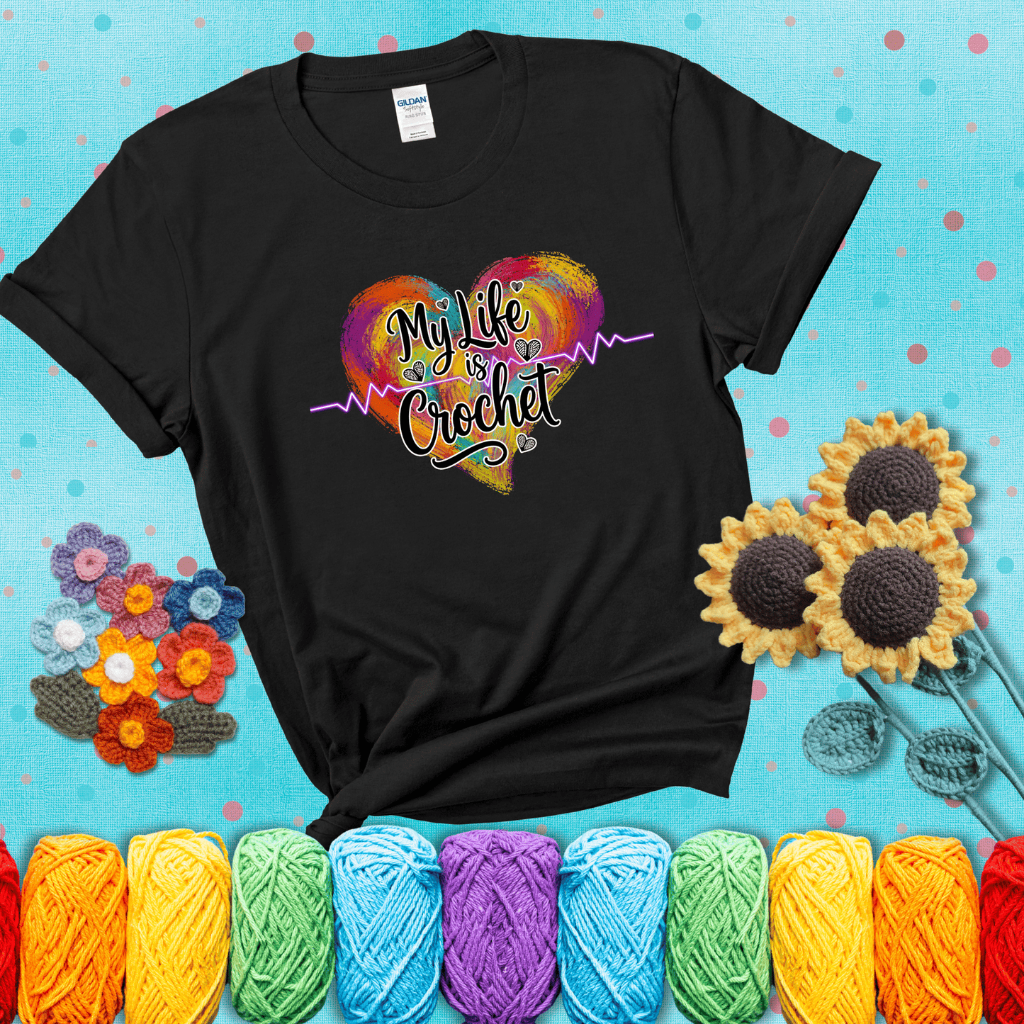 Colorful heart with an EKG line and text: “My Life is Crochet” in bold script showing a black tee with a teal sunflower background