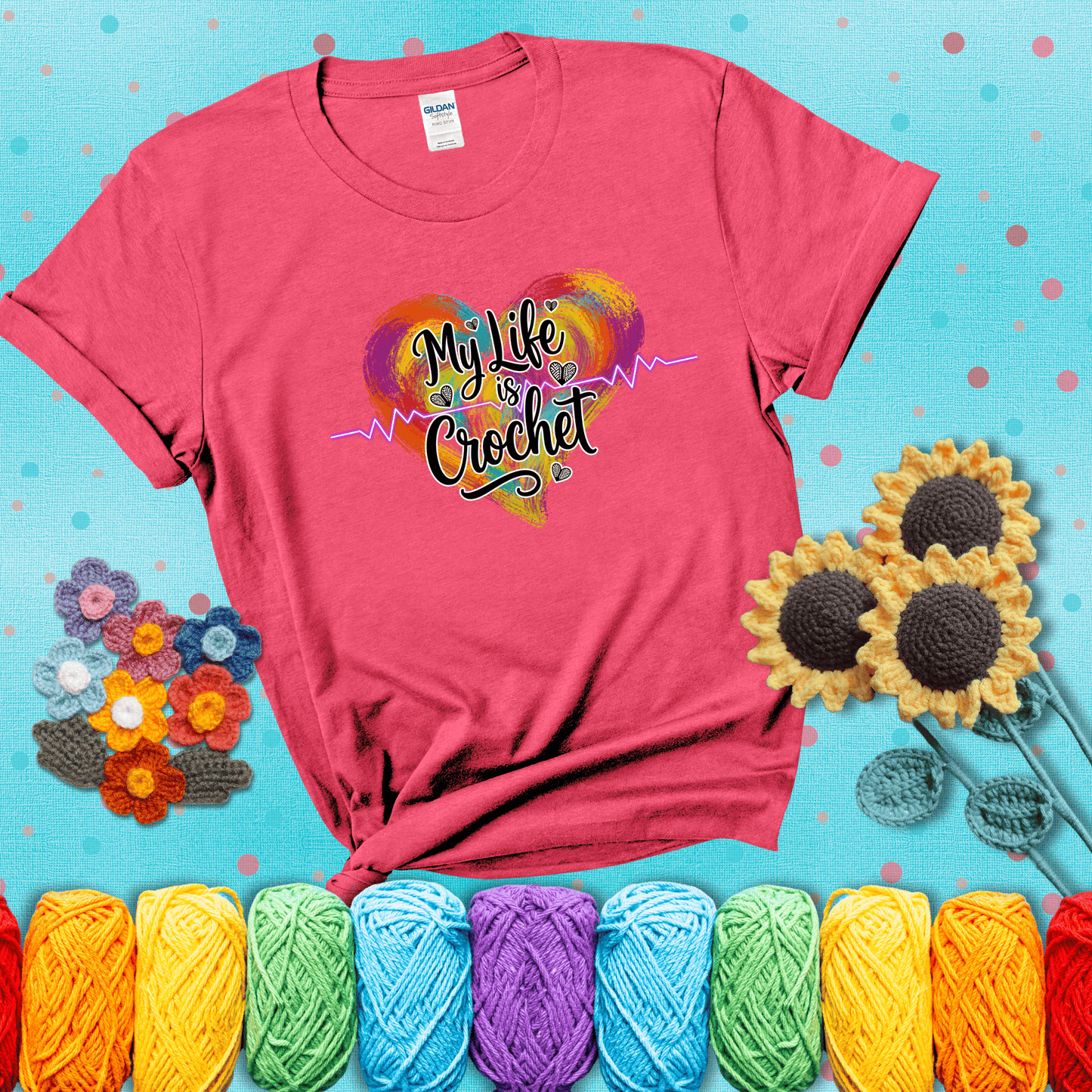 Colorful heart with an EKG line and text: “My Life is Crochet” in bold script showing a light red tee with a teal sunflower background