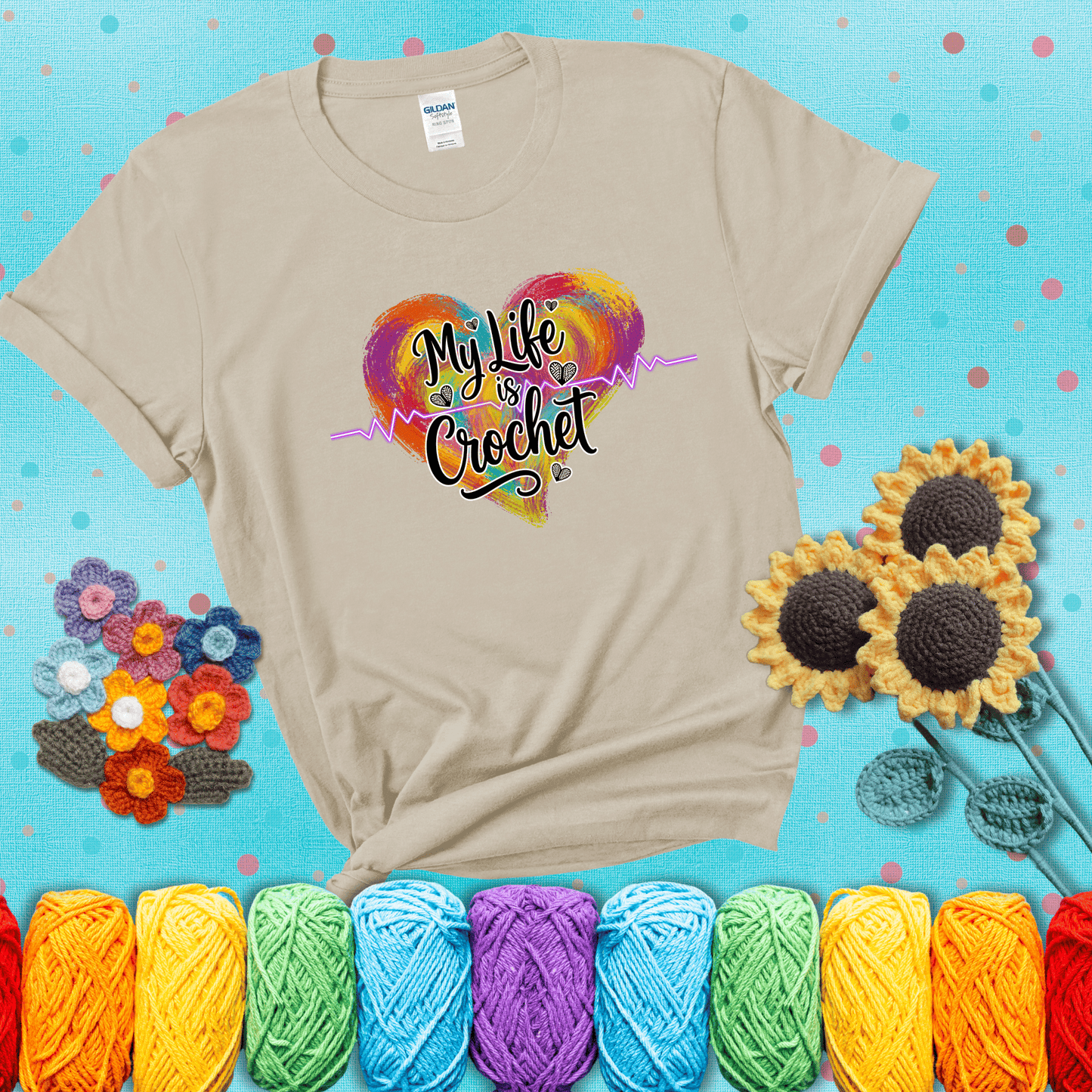 Colorful heart with an EKG line and text: “My Life is Crochet” in bold script showing a beige tee with a teal sunflower background