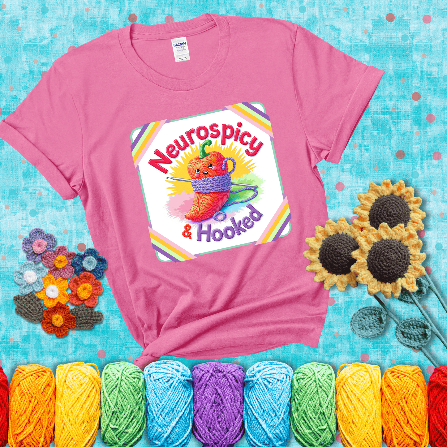 A cheerful red pepper wrapped in purple yarn with a crochet hook, framed by pastel rainbow corners and the words "Neurospicy & Hooked" showing a pink tee with a teal sunflower background