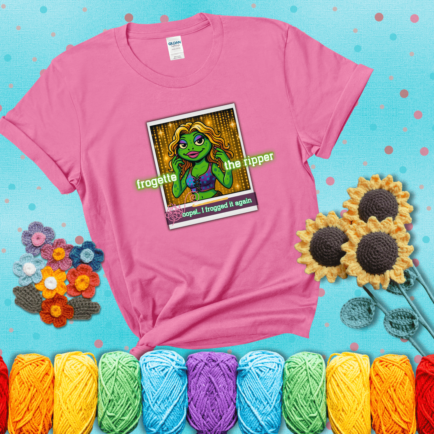 Retro-styled illustration of a glamorous green frog in a sparkly outfit, labeled "Frogette the Ripper" with the phrase “Oops! I frogged it again” below, referencing both crochet and pop culture showing a pink tee with a teal sunflower background
