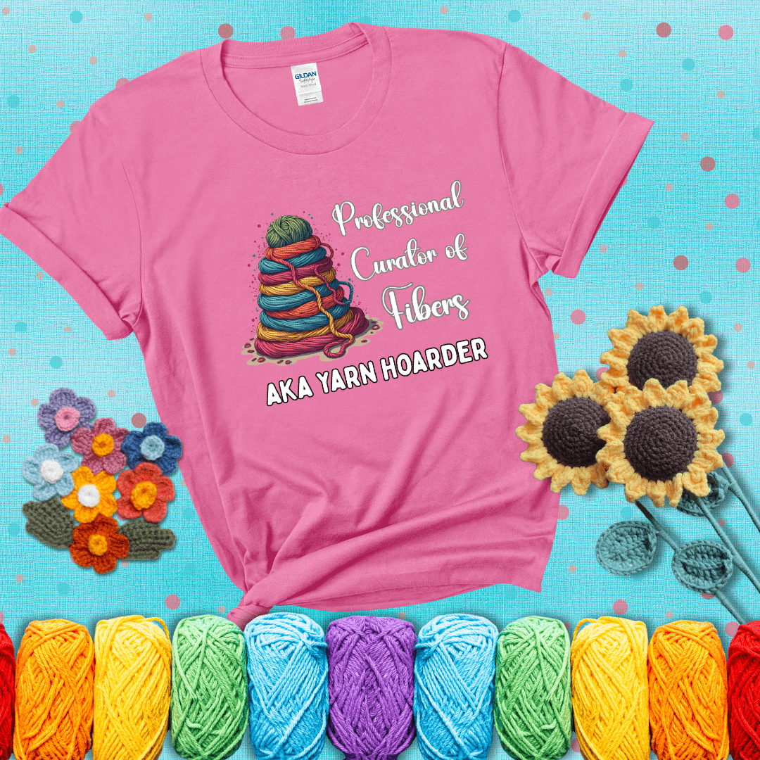Pyramid of rainbow yarn topped with green ball; text reads “Professional Curator of Fibers AKA Yarn Hoarder,” a playful shirt for serious stashers showing a pink tee with a teal sunflower background