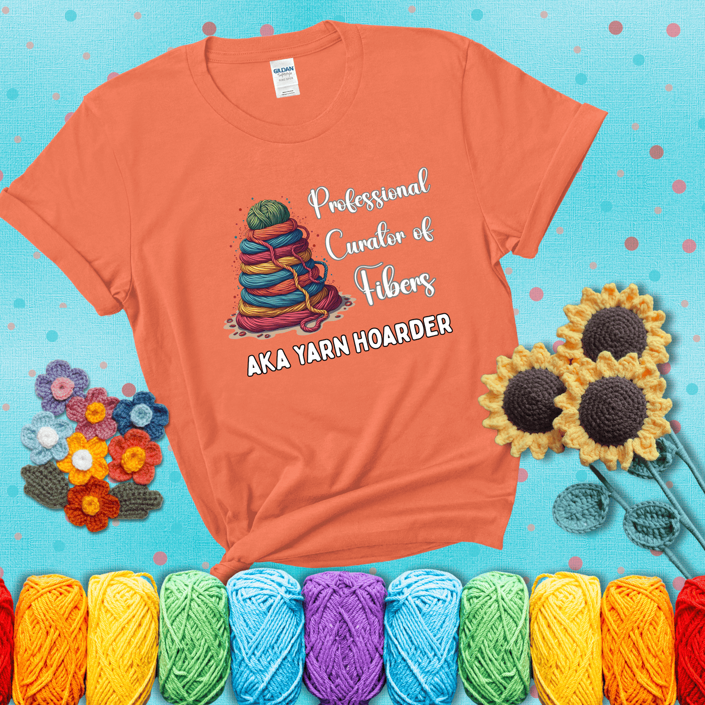 Pyramid of rainbow yarn topped with green ball; text reads “Professional Curator of Fibers AKA Yarn Hoarder,” a playful shirt for serious stashers showing a light orange tee with a teal sunflower background