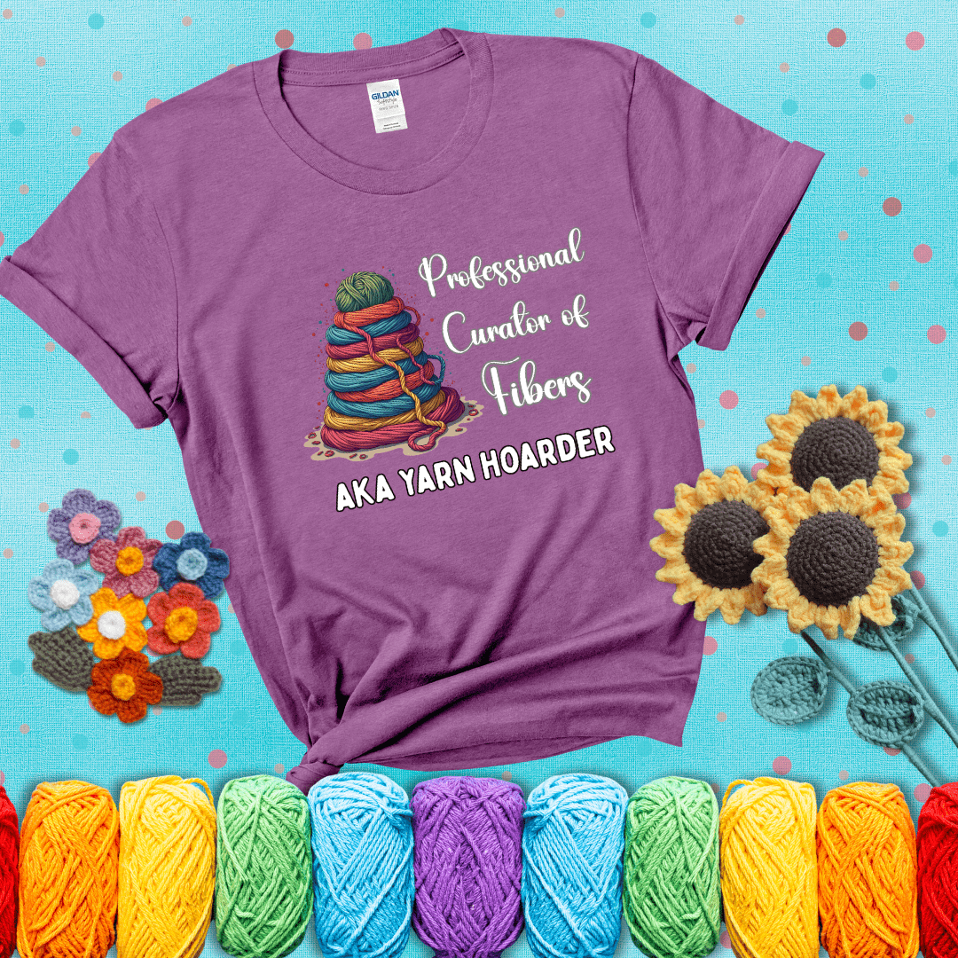 Pyramid of rainbow yarn topped with green ball; text reads “Professional Curator of Fibers AKA Yarn Hoarder,” a playful shirt for serious stashers showing a light purple tee with a teal sunflower background