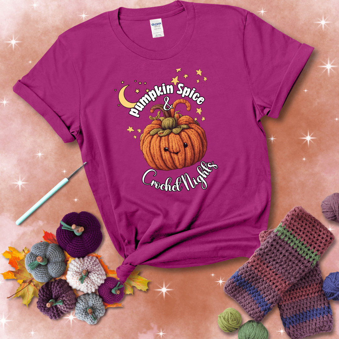 Smiling pumpkin crocheted with yarn texture, surrounded by stars and a crescent moon. Text reads “Pumpkin Spice & Crochet Nights” showing a magenta tee with a festive Fall background