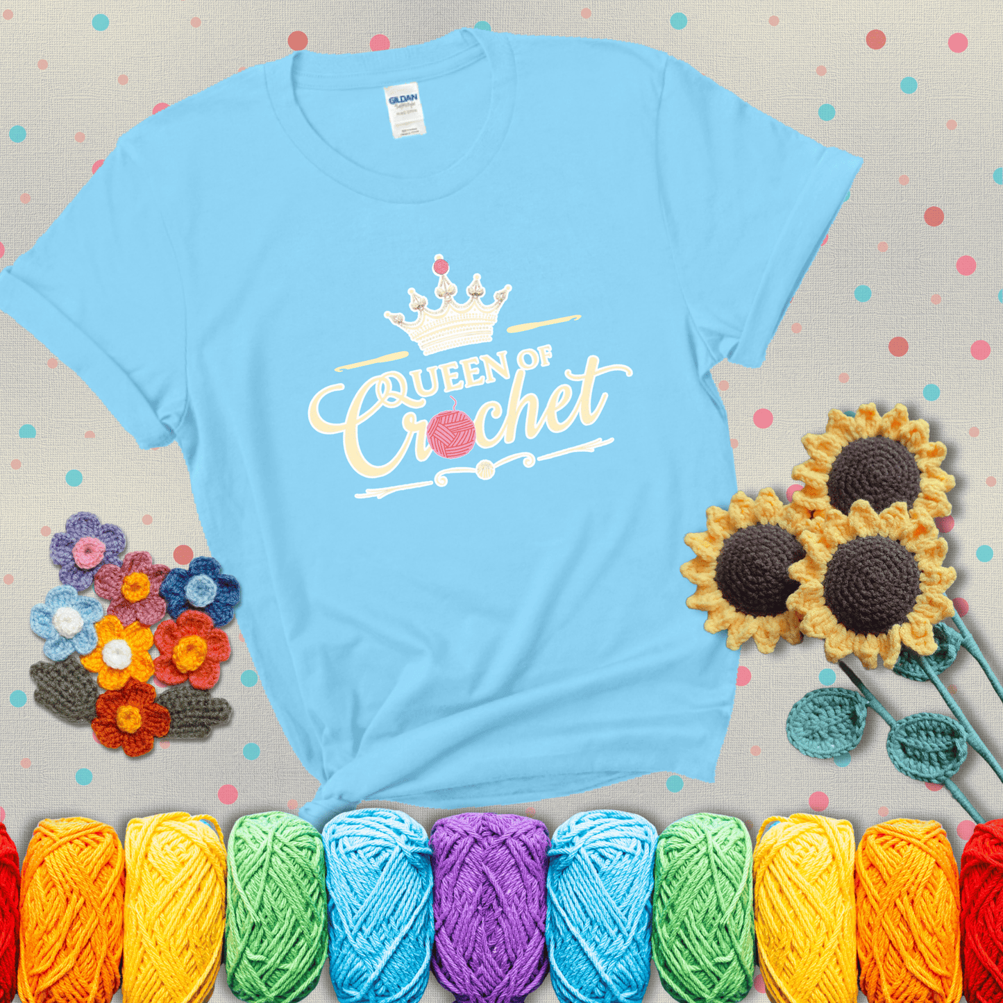 Crown-topped design reads “Queen of Crochet” with elegant script and two pink yarn balls, one forming the letter “o” and another atop the crown showing a light blue tee with grey sunflower background