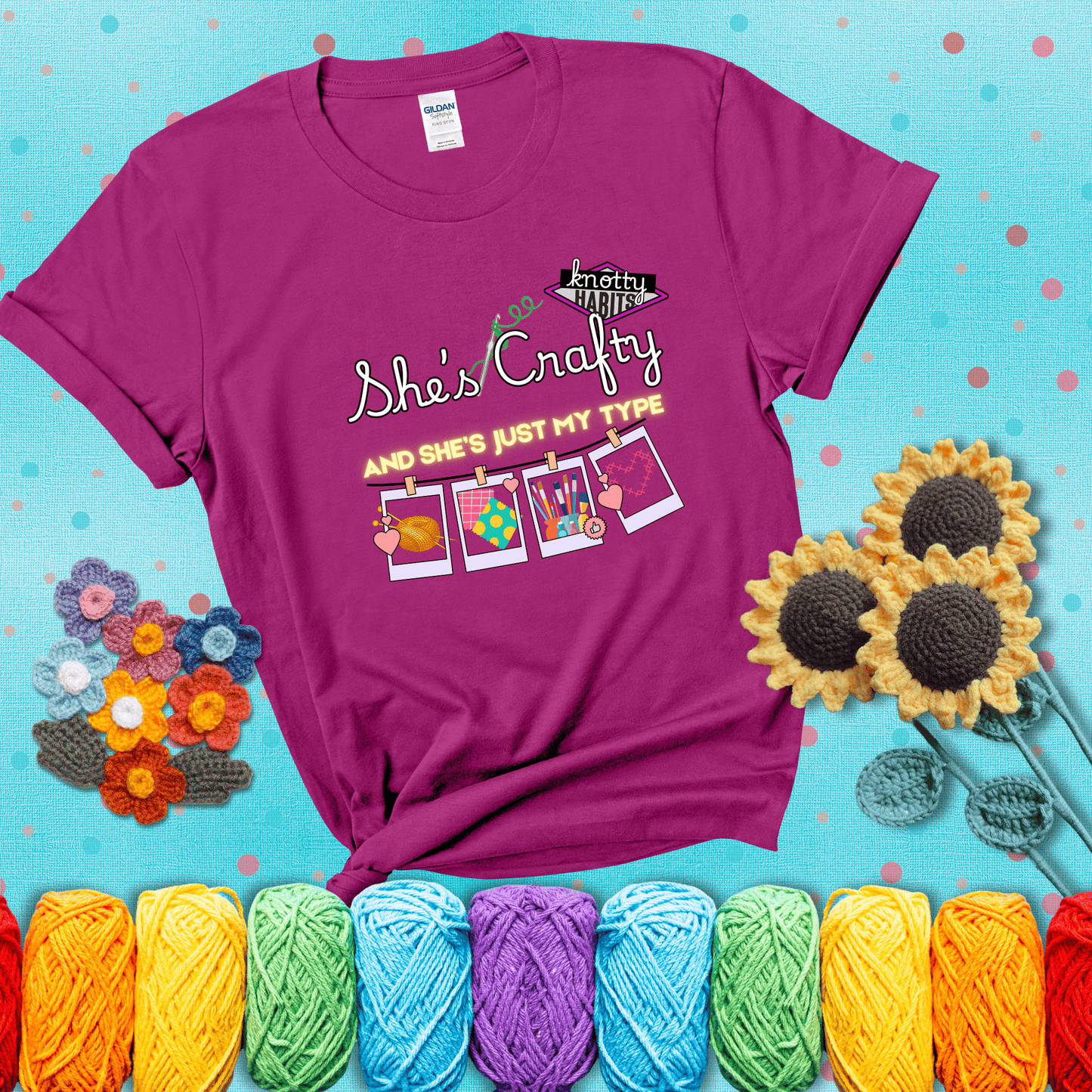 Text reads "She’s Crafty & She’s Just My Type" with yarn, fabric, painting, and cross-stitch icons hanging like Polaroids showing a magenta tee with a teal sunflower background