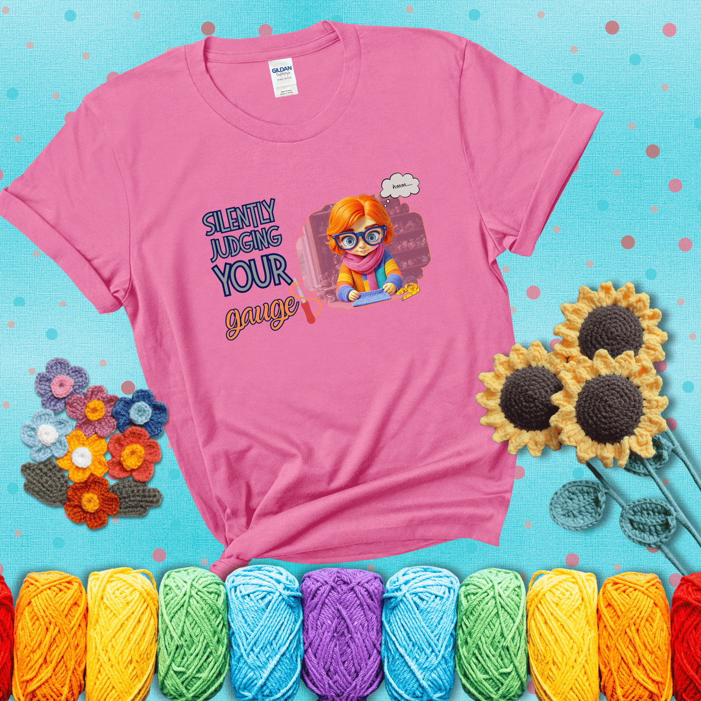 A serious-looking crocheter with rainbow clothes, big glasses, and a tape measure silently examines their stitches under the phrase “Silently judging your gauge” showing a pink tee with a teal sunflower background