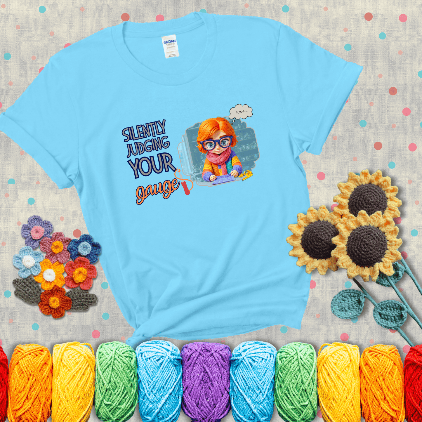 A serious-looking crocheter with rainbow clothes, big glasses, and a tape measure silently examines their stitches under the phrase “Silently judging your gauge” showing a light blue tee with grey sunflower background