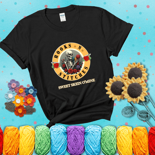 A skeleton holding colorful yarn, surrounded by roses, framed in a circular logo-style design that says “Hooks 'N Stitches” and “Sweet Skein O’Mine,” with crochet hooks piercing through showing a black tee with a teal sunflower background