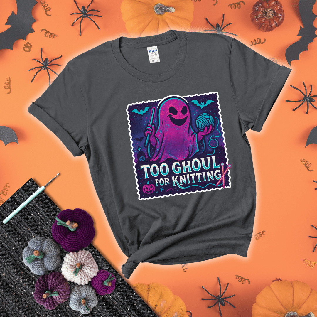 A spooky ghost holds a yarn ball and crochet hook in a vibrant Halloween palette with bats, tombstones, and pumpkins wearing a dark grey tee with a festive halloween background