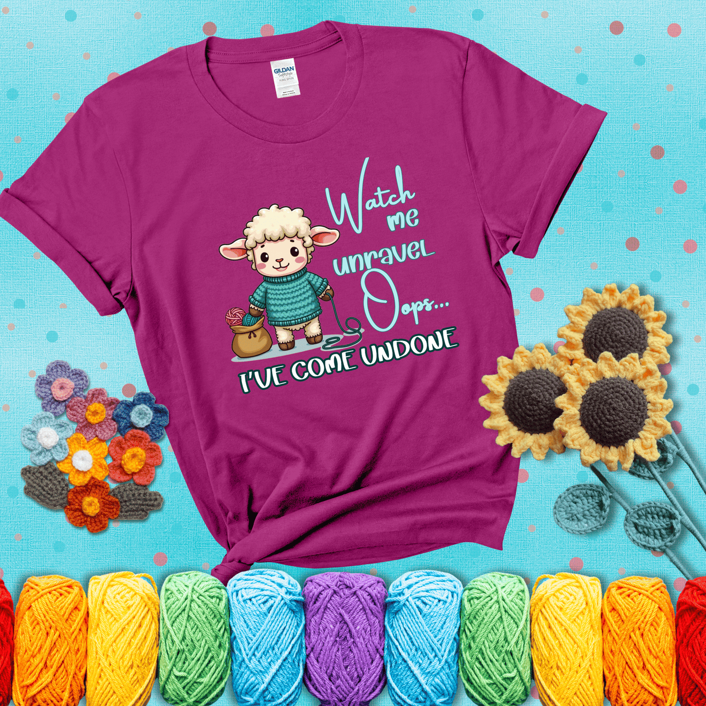 Cute sheep holding yarn looks startled with the phrase “Watch me unravel… Oops, I’ve come undone.” Perfect mix of whimsy and yarn life chaos, showing a magenta tee with a teal sunflower background