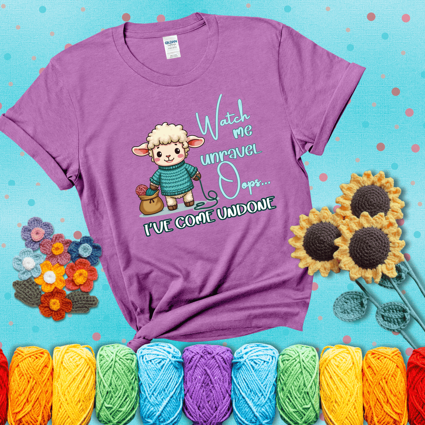 Cute sheep holding yarn looks startled with the phrase “Watch me unravel… Oops, I’ve come undone.” Perfect mix of whimsy and yarn life chaos, showing a light purple tee with a teal sunflower background