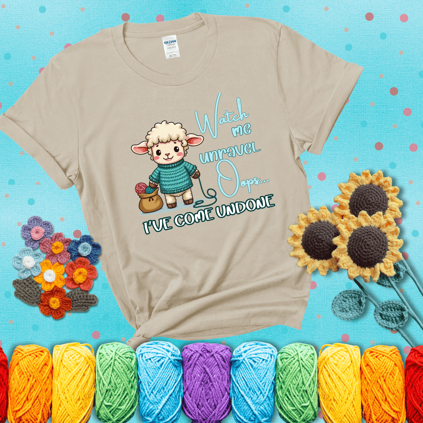 Cute sheep holding yarn looks startled with the phrase “Watch me unravel… Oops, I’ve come undone.” Perfect mix of whimsy and yarn life chaos, showing a beige tee with a teal sunflower background