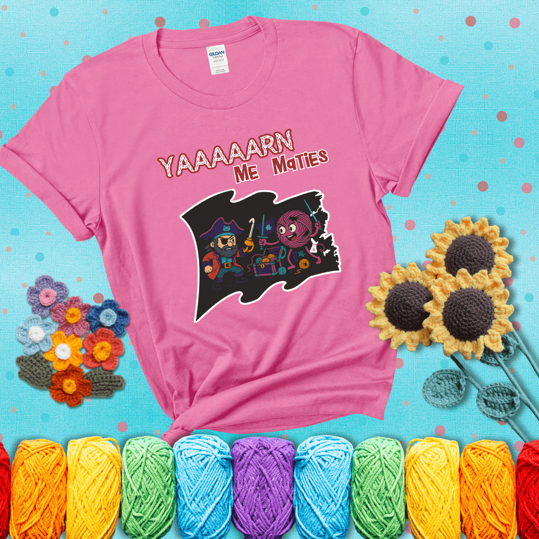 A pirate with a crochet hook for a hand duels a fierce yarn ball wielding knitting needles, standing in front of a treasure chest filled with yarn showing a pink tee with a teal sunflower background