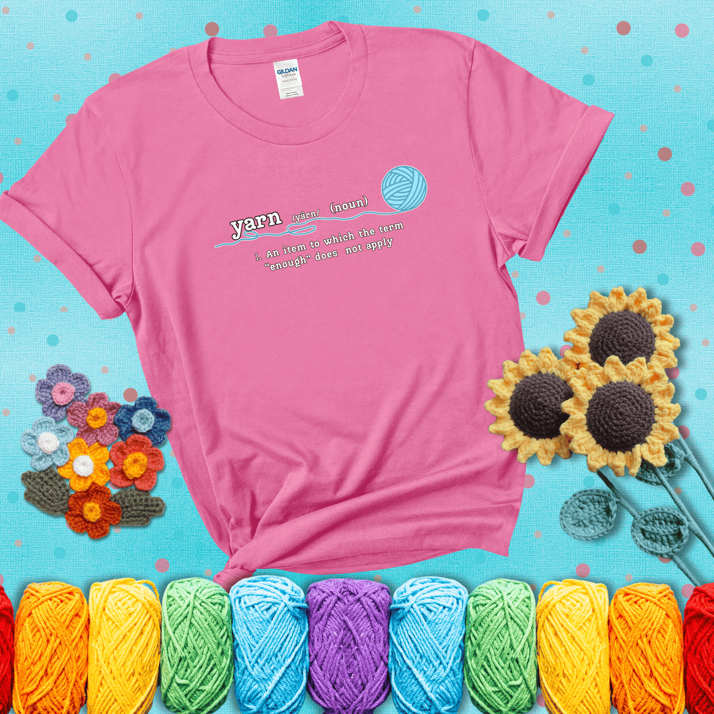 A definition-style graphic showing the word "yarn" as a noun, with the definition “An item to which the term ‘enough’ does not apply,” and a ball of blue yarn with a loose strand showing a pink tee with a teal sunflower background