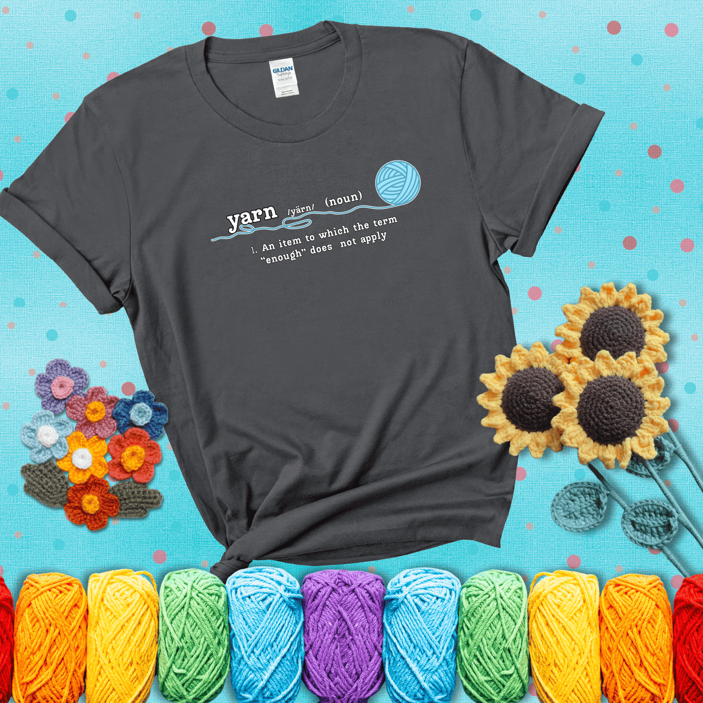 A definition-style graphic showing the word "yarn" as a noun, with the definition “An item to which the term ‘enough’ does not apply,” and a ball of blue yarn with a loose strand showing a dark grey tee with a teal sunflower background