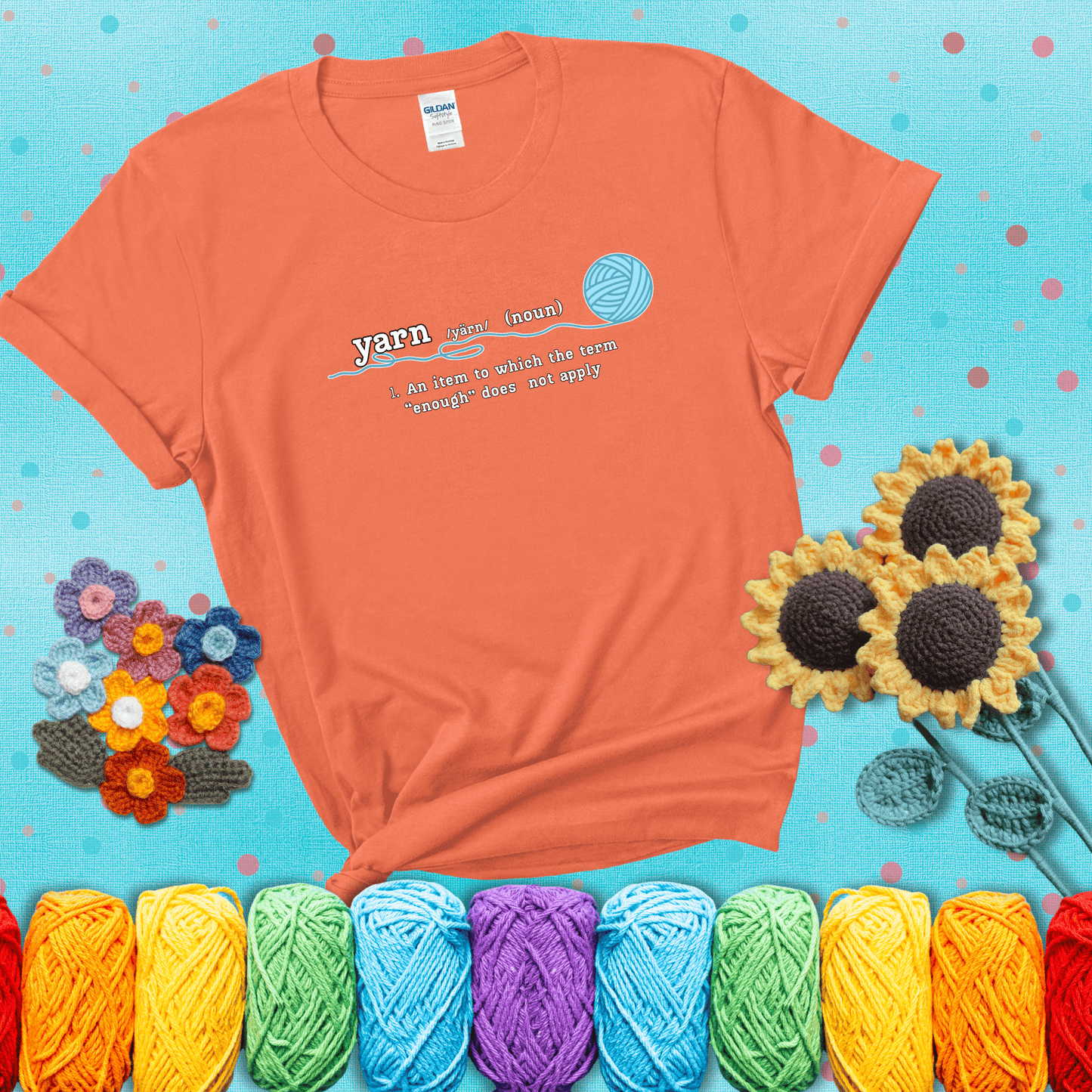 A definition-style graphic showing the word "yarn" as a noun, with the definition “An item to which the term ‘enough’ does not apply,” and a ball of blue yarn with a loose strand showing a light orange tee with a teal sunflower background
