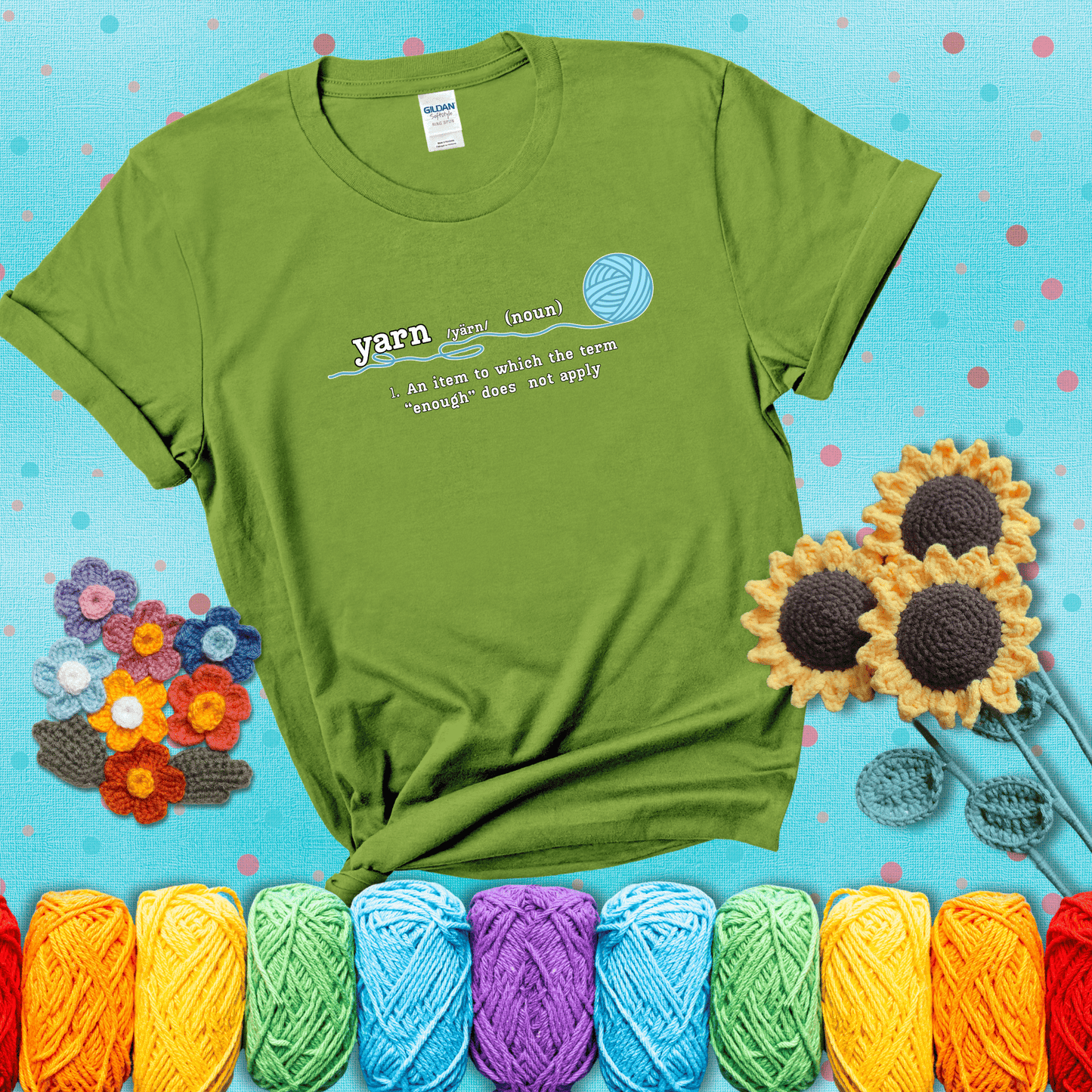 A definition-style graphic showing the word "yarn" as a noun, with the definition “An item to which the term ‘enough’ does not apply,” and a ball of blue yarn with a loose strand showing a bright green tee with a teal sunflower background