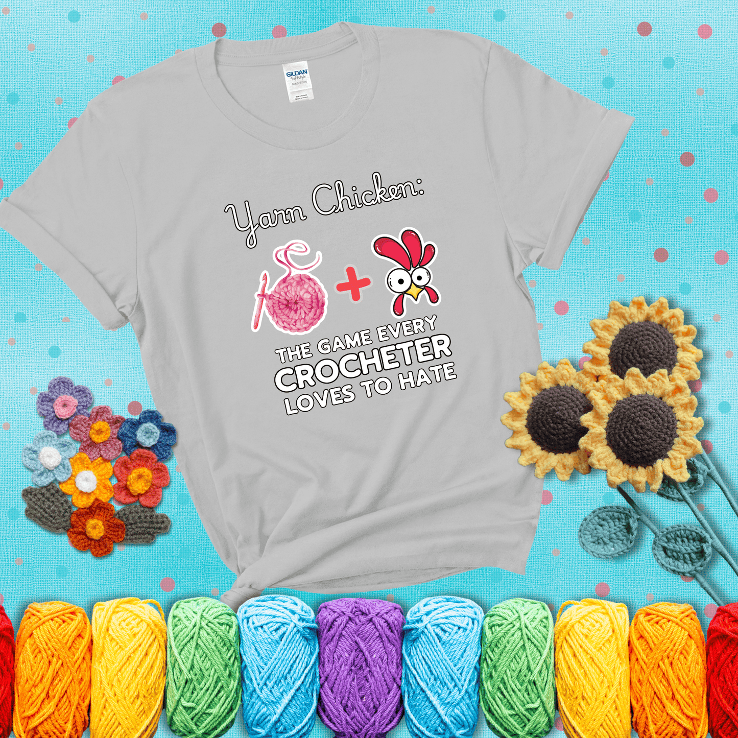 Cartoon chicken inside a yarn ball with crochet circle background. Text reads: “Yarn Chicken: The Game Every Crocheter Loves to Lose.” A fun and relatable tee for fiber artists who like to live on the edge, showing a light grey tee with a teal sunflower background