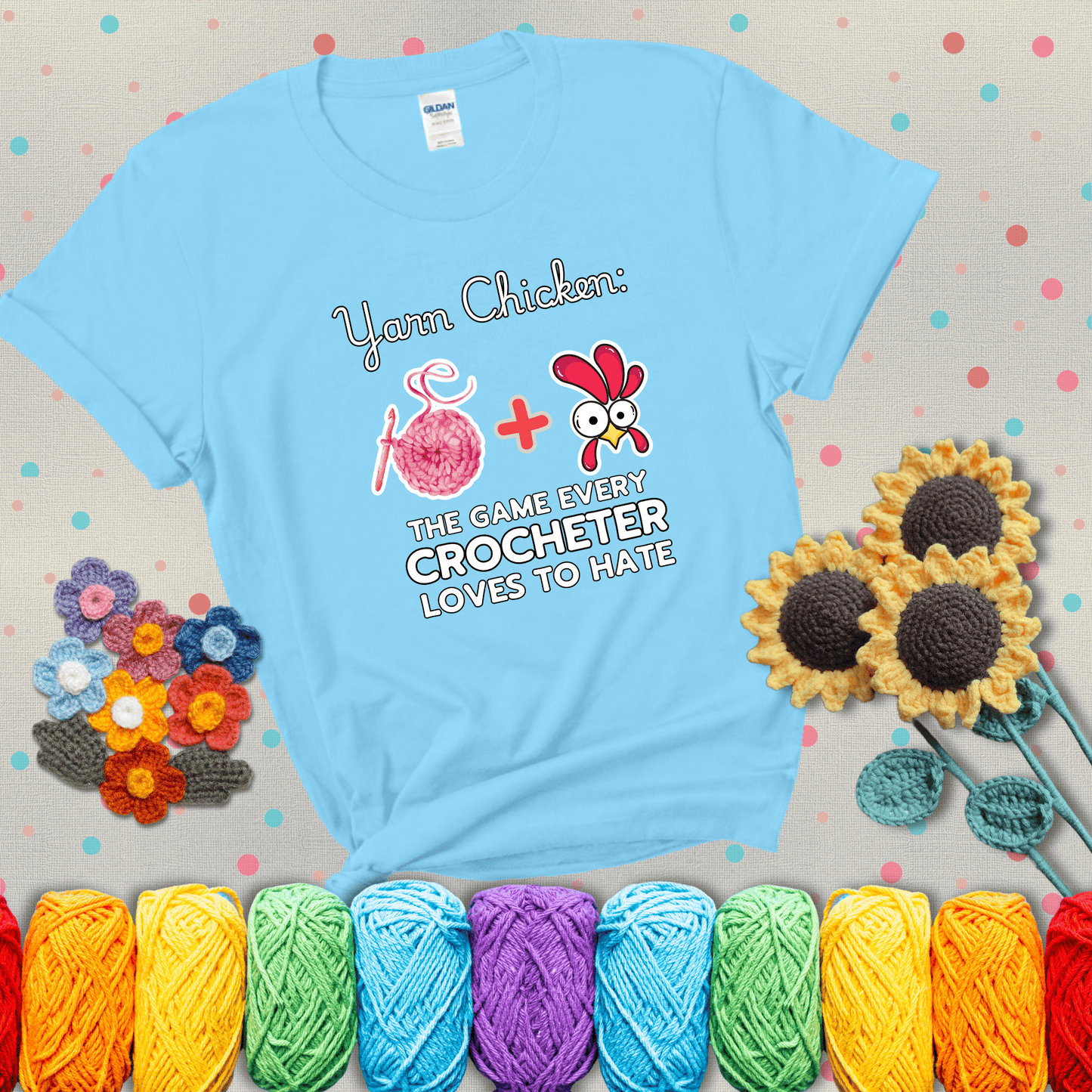 Cartoon chicken inside a yarn ball with crochet circle background. Text reads: “Yarn Chicken: The Game Every Crocheter Loves to Lose.” A fun and relatable tee for fiber artists who like to live on the edge, showing a light blue tee with grey sunflower background