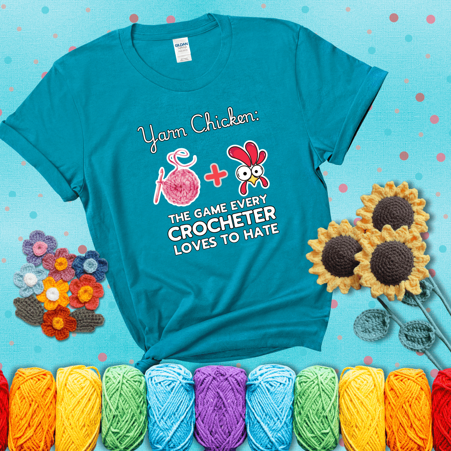 Cartoon chicken inside a yarn ball with crochet circle background. Text reads: “Yarn Chicken: The Game Every Crocheter Loves to Lose.” A fun and relatable tee for fiber artists who like to live on the edge, showing a blue-green tee with a teal sunflower background