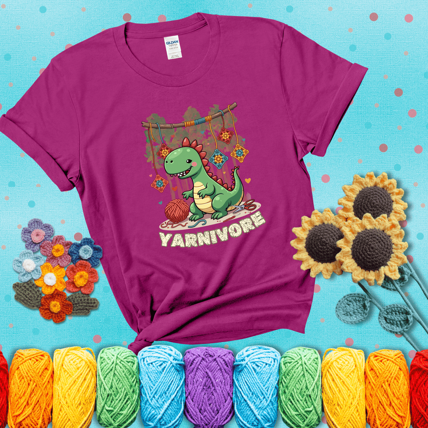 Silly dinosaur chomping on yarn skeins. Text reads: “Yarnivore.” A fun and quirky tee for yarn-obsessed crafters with big appetites, showing a magenta tee with a teal sunflower background