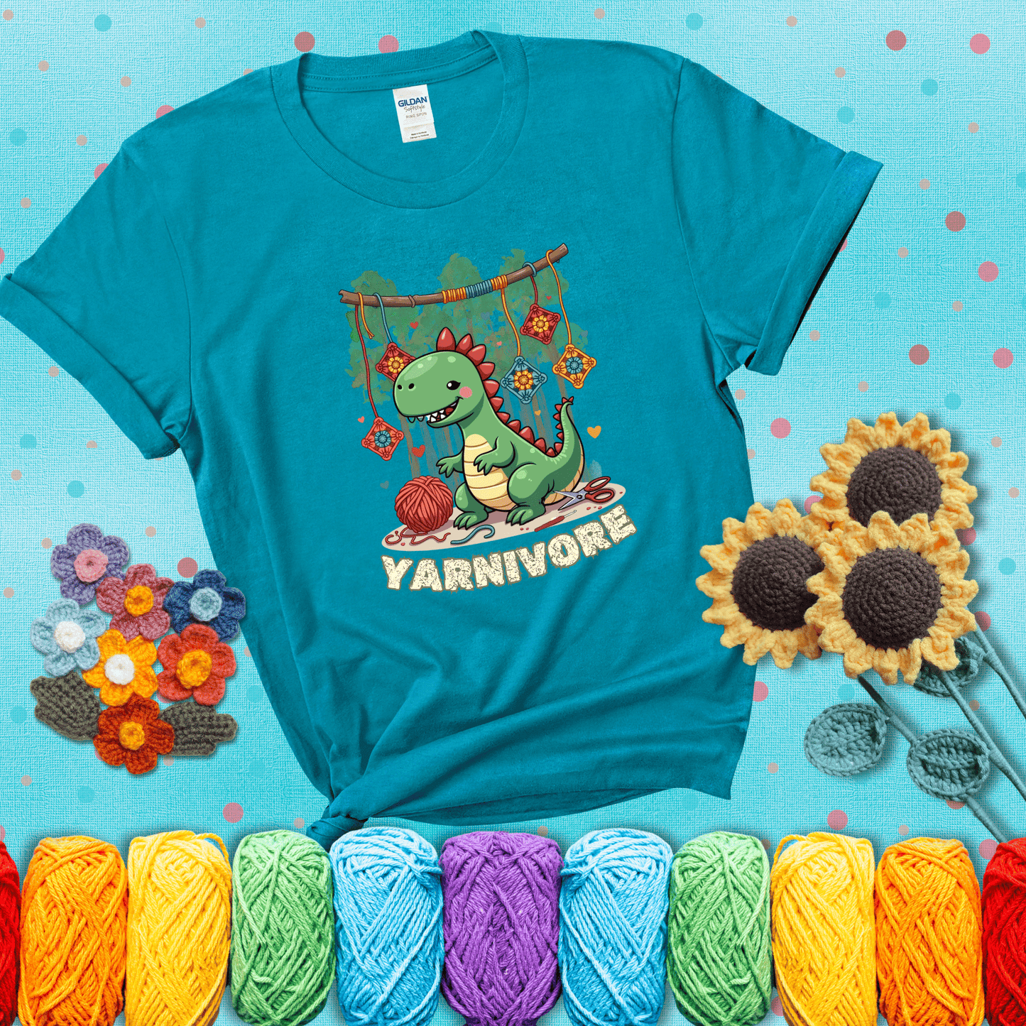 Silly dinosaur chomping on yarn skeins. Text reads: “Yarnivore.” A fun and quirky tee for yarn-obsessed crafters with big appetites, showing a blue-green tee with a teal sunflower background