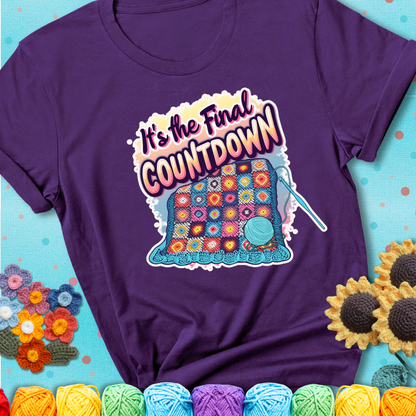 Purple t-shirt with a colorful crochet blanket in progress, blue yarn ball, crochet hook, and the phrase “It’s The Final Countdown.”