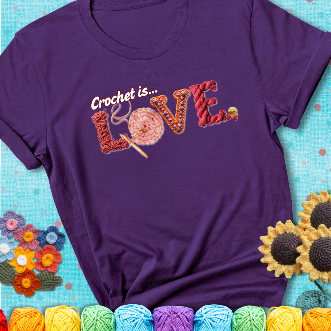 A purple t-shirt featuring the word "LOVE" spelled with different crochet textures and yarn in red tones, with the phrase “Crochet is…” above in script.