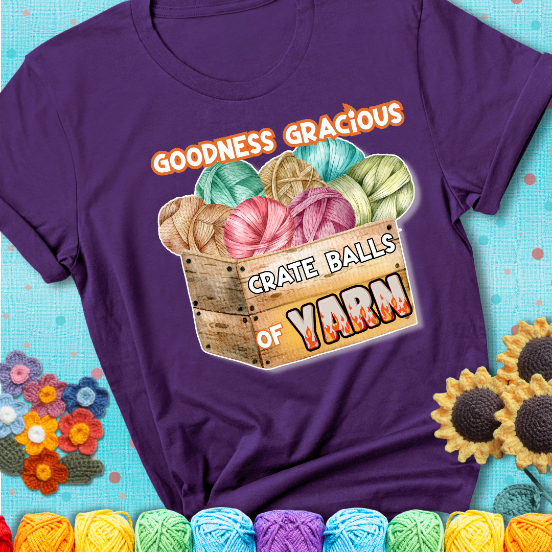 Wooden crate filled with colorful yarn balls and bold text “Goodness Gracious, Crate Balls of Yarn” with flame effects, a funny gift for crocheters showing a purple tee with a teal sunflower background