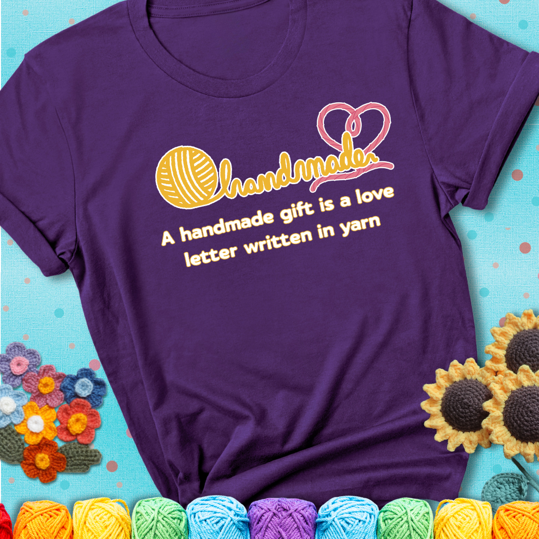 Soft script-style design with heart detail. Text reads: “A Handmade Gift Is a Love Letter Written in Yarn.” A sweet and sentimental shirt for crocheters who craft from the heart, showing a purple tee with a teal sunflower background
