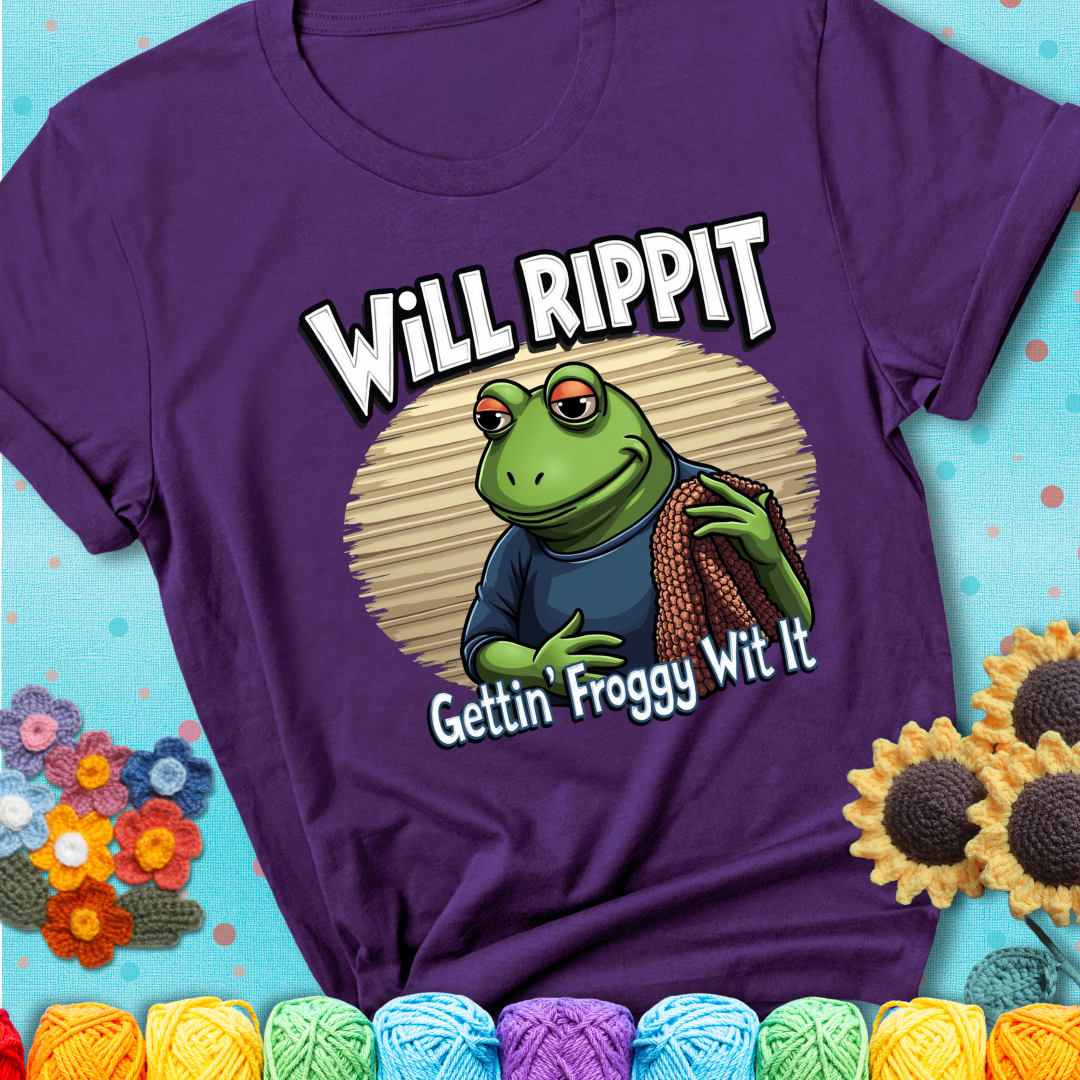 Cool frog holding a yarn blanket. Text reads: “Will Rippit Gettin’ Froggy Wit It.” A hip and humorous crochet purple tee for yarn lovers with rhythm.