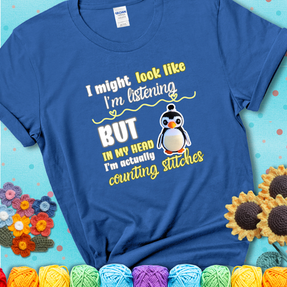 Blue t-shirt shows a crocheted penguin next to the text “I might look like I’m listening but in my head I’m actually counting stitches.”