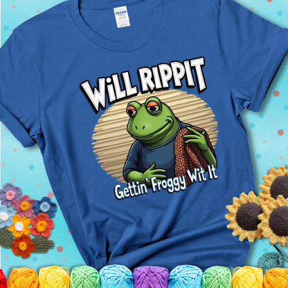 Cool frog holding a yarn blanket. Text reads: “Will Rippit Gettin’ Froggy Wit It.” A hip and humorous crochet blue tee for yarn lovers with rhythm.