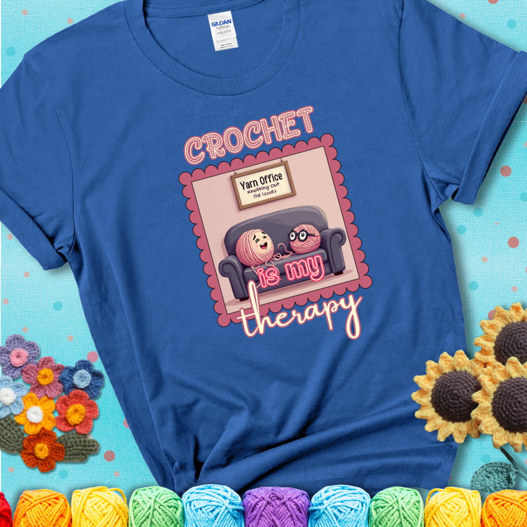 Blue t-shirt showing a simple text design with yarn cartoon figures. Text reads: “Crochet is My Therapy.” A calming tee for fiber lovers who find healing in every stitch.